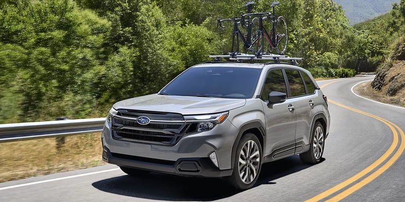 Silver 2026 Subaru Forester with bike rack driving down road