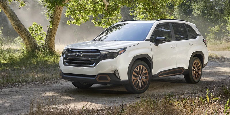 White 2026 Subaru Forester driving near woods